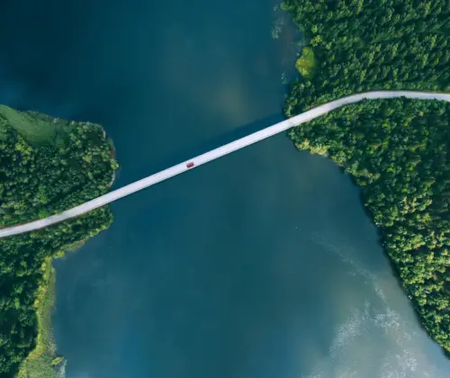 Roadtrip durch Europa, eine lange Brücke über einem breiten Fluss, die Straße verläuft durch dichte grüne Wälder