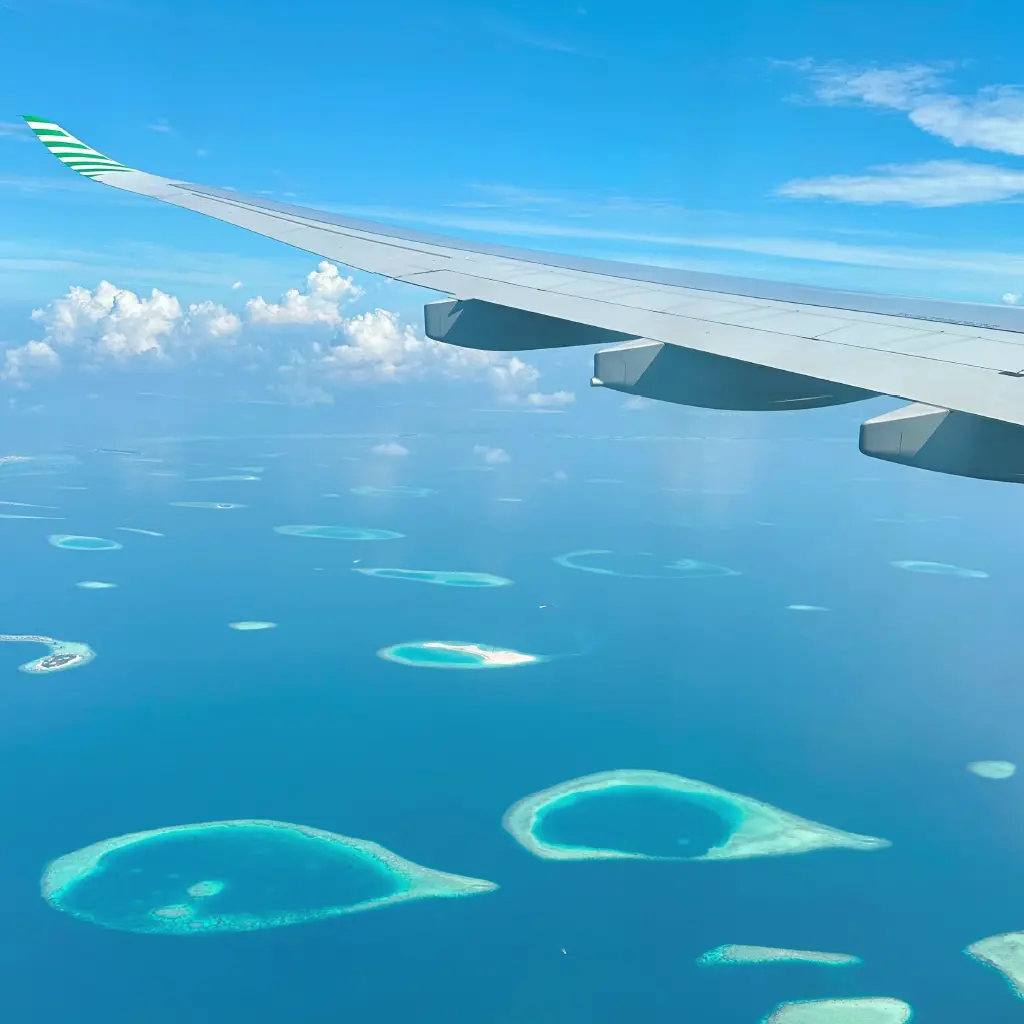 Flug über die Malediven in einem Reiseflugzeug, eine Menge vereinzelte Inseln verteilt in tiefblauem Wasser