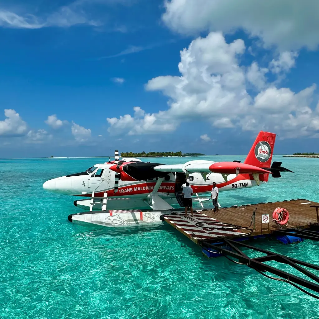 Wasserflugzeugtrip auf den Malediven, ein Flugzeug, das am Steg geparkt in türkisblauem Wasser steht